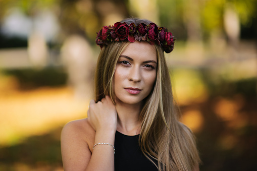Portrait of a beautiul young woman wearing a  floral head wreath outdoors