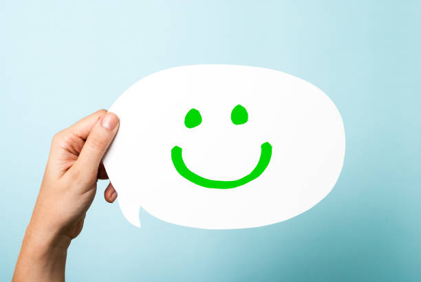 Blue happy face emoji surrounded by yellow happy face emojis. Horizontal composition.