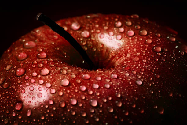 istock Red apple in drops of water on a black background close-up. 1284445671