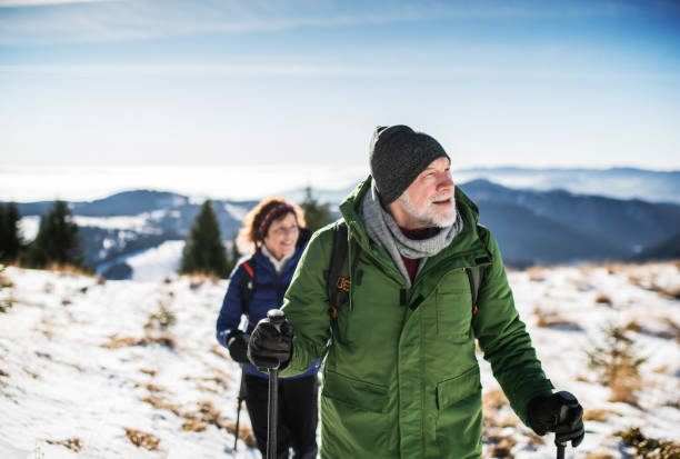 pareja mayor con bastones nórdicos de senderismo en la naturaleza de invierno cubierta de nieve. - snow hiking fotografías e imágenes de stock