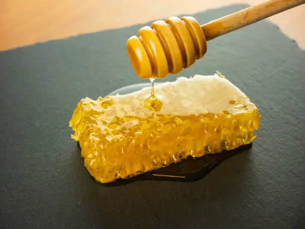 honeycomb with honey dipper on black slate plate still life honey food