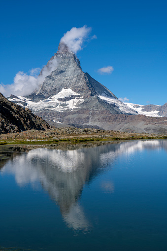 The Matterhorn with reflection from the Riffelsee lake and clouds - Vertical shot - Zermatt Switzerland