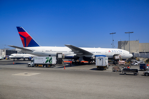 Delta Air Lines Boeing 777-232ER aircraft N861DA parked at gate being catered and loaded up with cargo at Los Angeles International Airport in April 2020.