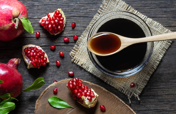istock Pomegranate molasses in glass bowl with fresh ripe whole and split pomegranate fruit on wooden rustic table 1284456769