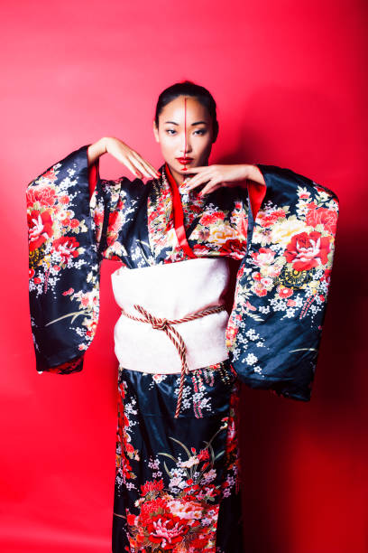young pretty geisha on red background posing in kimono, oriental concept young pretty geisha on red background posing in kimono, oriental concept closeup modern geisha stock pictures, royalty-free photos & images