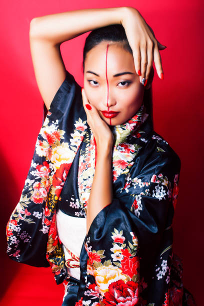 young pretty geisha on red background posing in kimono, oriental concept young pretty geisha on red background posing in kimono, oriental concept closeup modern geisha stock pictures, royalty-free photos & images