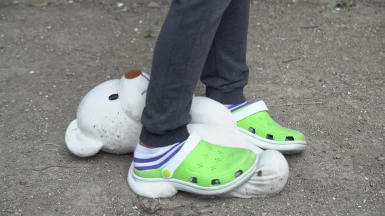 A boy kicking his teddy bear.