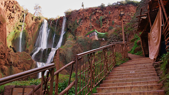 Stairs with a metal railing with a lantern leading up to a viewpoint on Ouzoud Falls near Ouzoud, Morocco, a popular tourist destination.