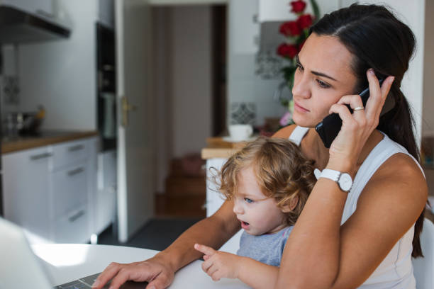 istock Frowning young woman holding a child and having a phone conversation 1284463824