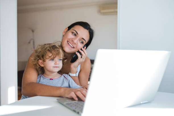 istock Woman talking via smart phone and using laptop when holding child in her lap 1284463855