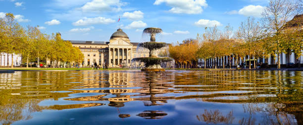 Kurhaus Wiesbaden (Health Spa) and park in autumn with fountain and panoramic view Wiesbaden, Germany, 10/31/2020: Kurhaus or cure house spa and casino building and Bowling Green park with grass lawn, trees alley and pond with fountain in historical city centre, State of Hesse kurhaus casino stock pictures, royalty-free photos & images