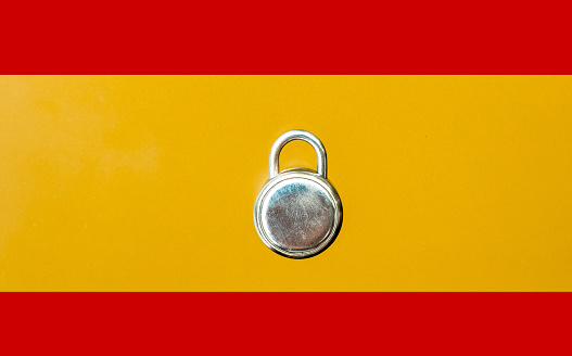 Concept Of Second Lockdown in Spain. Real padlock placed on top of flag of Spain to indicate second national lockdown in the country due to rise in COVID-19 cases.