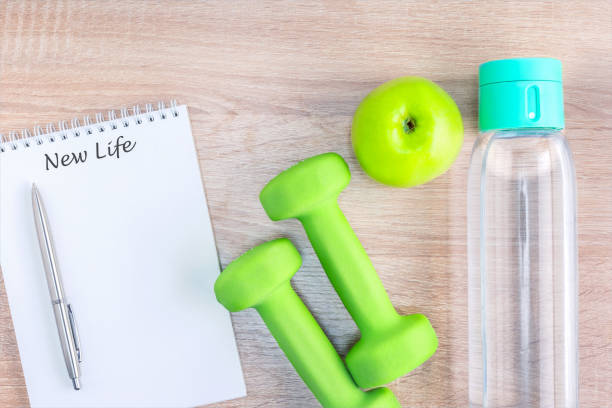 istock New life written on Notebook and dumbbells, fruit, drink water on wooden surface. Top view. 1284491005