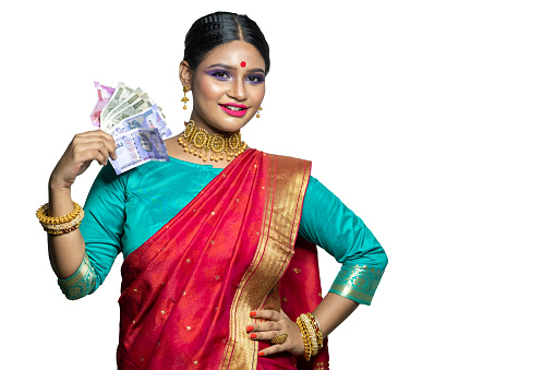 Happy young traditional woman holding Indian rupee notes against, Studio shot isolated on white background