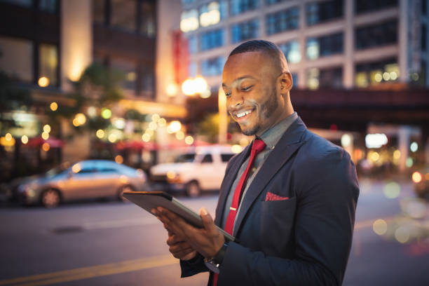 istock Smiling Businessman checking News on Digital Tablet Computer Chicago at Night 1284500915