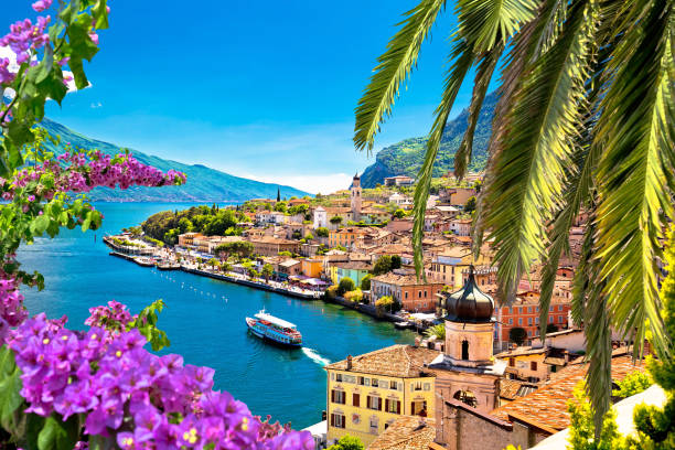 istock Limone sul Garda waterfront viewthrough flowers and palm tree 1284501153