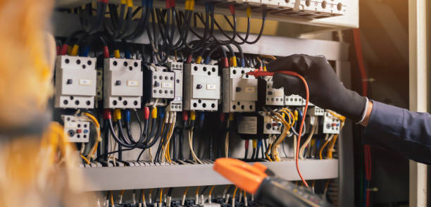 Electrician engineer work tester measuring voltage and current of power electric line in electical cabinet control.and wires on relay protection system. Bay control unit. Medium voltage switchgear.