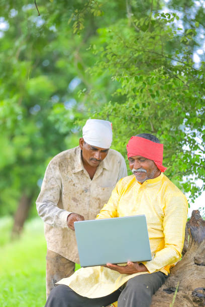 istock Indian farmer using laptop at field and showing some information to labor 1284507009