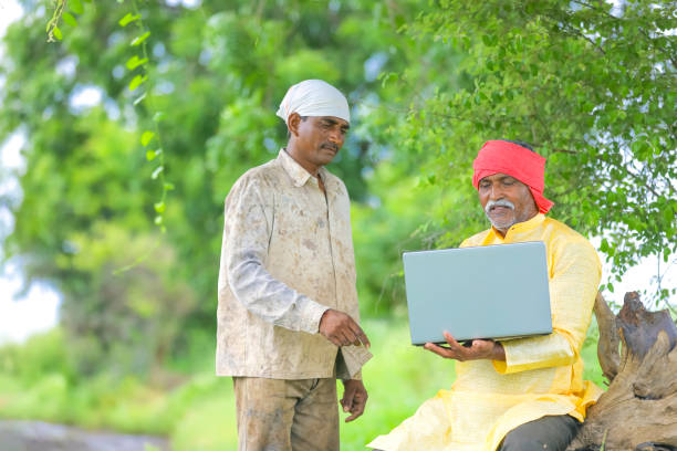 istock Indian farmer using laptop at field and showing some information to labor 1284507020