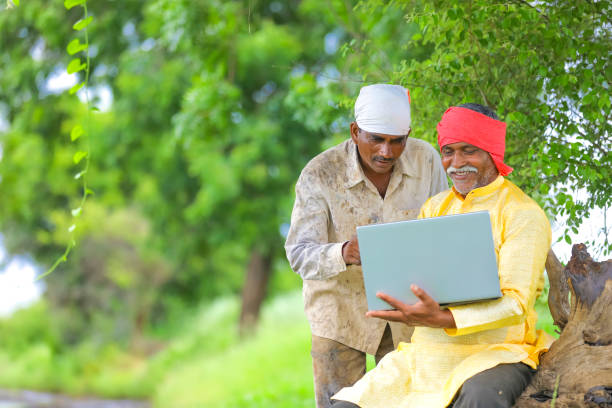 istock Indian farmer using laptop at field and showing some information to labor 1284507606