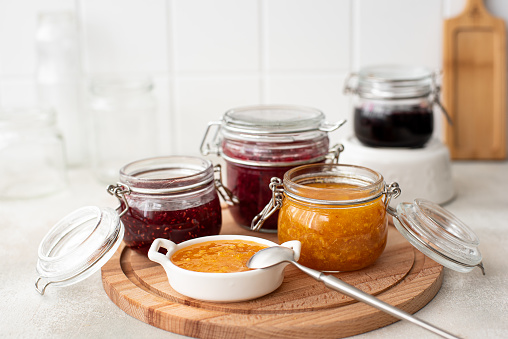 homemade raspberry, tangerine and blackberry jam in glass jars