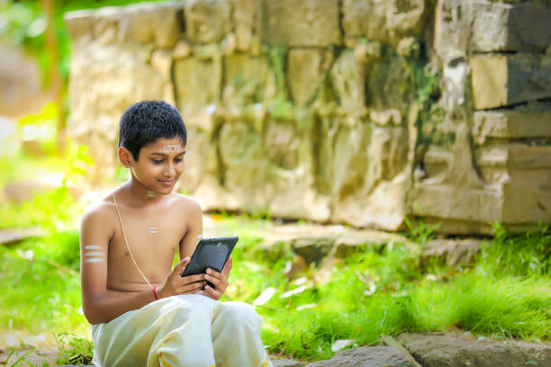 el niño sacerdote indio usando el teléfono inteligente - caste system fotografías e imágenes de stock