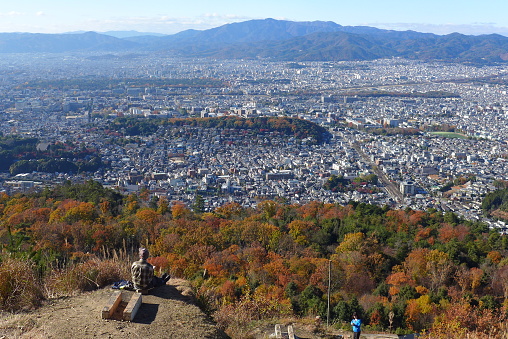 Kyoto, Kyoto, Japan - December 8, 2015: The photo shows a cityscape of Kyoto in autumn.　Hikers enjoy gazing at the city with the autumn leaves from a hill.