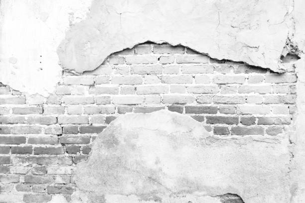 istock Black and white background concept, Old white masonry is cracking and decaying. The abstract white interior of an old broken brick wall for background, Shabby Building Facade With Damaged Plaster. 1284513577