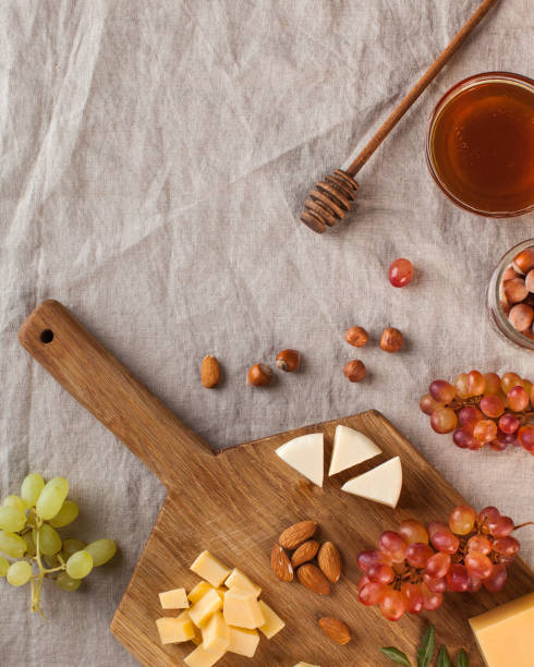 Cheese plate. Assorted cheeses on a wooden Board with grapes, honey, nuts on a linen tablecloth. Copy space.