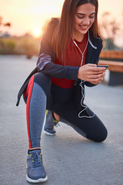 istock Modern young woman with cellphone making pause during jogging / exercise. 1284516991