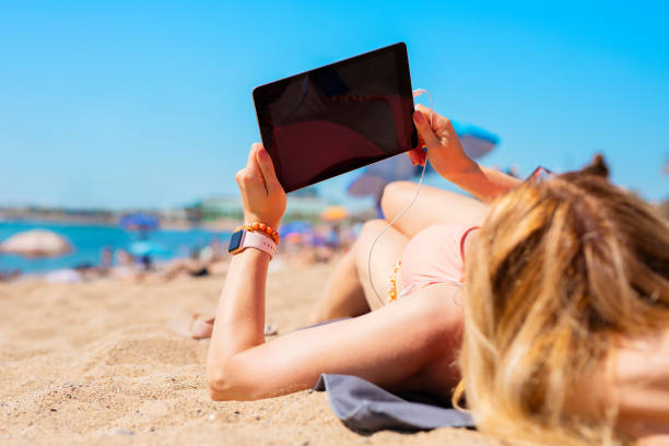 istock Woman using tablet on the beach in hot summer day 1284519095
