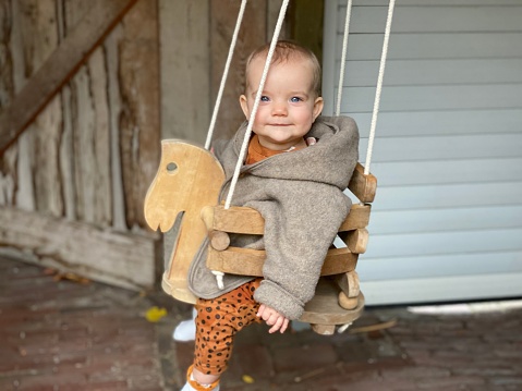 Baby girl having fun with his grandmother on the swing set