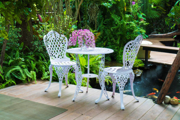 장식 정원 배경의 금속 의자와 테이블. 공원의 골동품 강철 의자와 테이블 - iron table 뉴스 사진 이미지