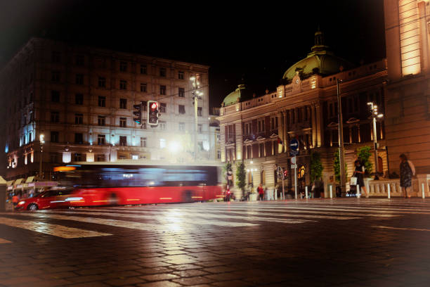 Pedestrian crossing in the historic center of Belgrade, red bus on the road and blurred figures of people in the night city Pedestrian crossing in the historic center of Belgrade, red bus on the road and blurred figures of people in the night city knez mihailova stock pictures, royalty-free photos & images