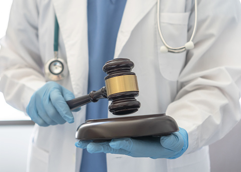 Forensic medicine, science or criminalistics legal investigation or medical practice - malpractice justice concept with judge gavel in hands of lab scientist or doctor for criminal and civil laws