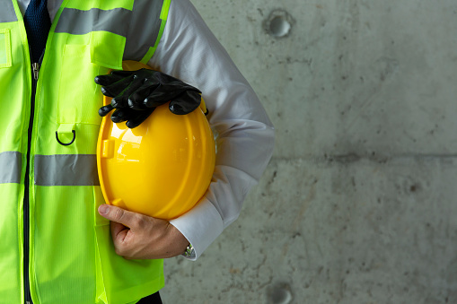 Retrato del trabajador de la construcción sosteniendo el casco amarillo de cerca photo