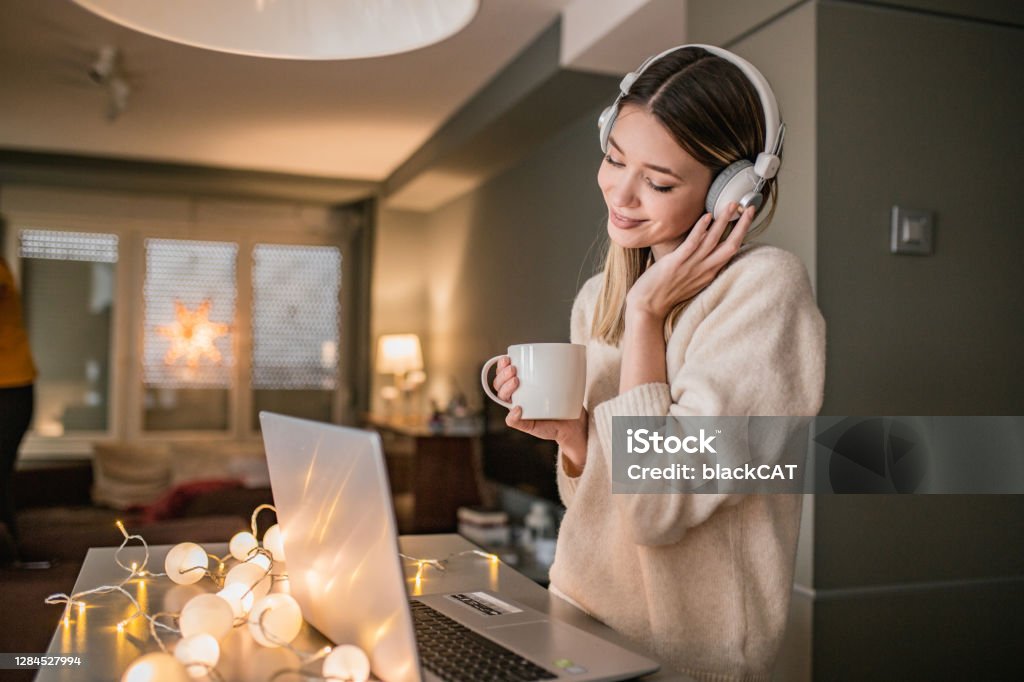 Young woman is using laptop at home A young woman is at home, using laptop, and shopping online Wireless Headphones Stock Photo