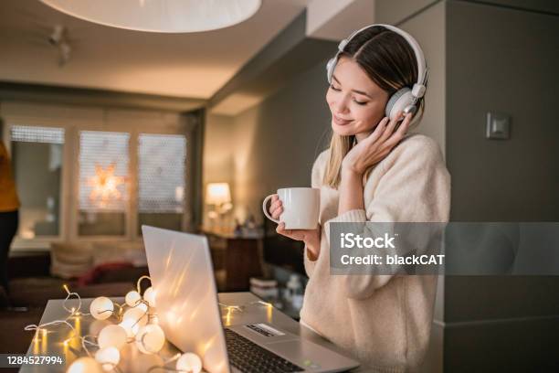 Young Woman Is Using Laptop At Home Stock Photo - Download Image Now - Wireless Headphones, Winter, Domestic Life