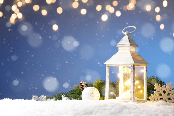 istock White Christmas lantern in snow, with yellow candle light, on blue background 1284529586