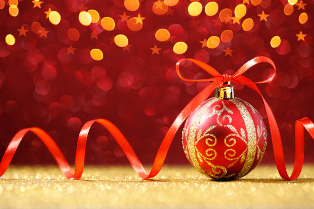 istock Red Christmas ball on red glitter background with gold lights 1284530361