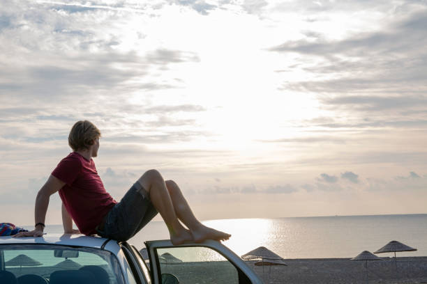 istock Young man relaxes on car at beach in the morning 1284534391
