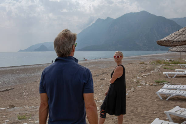 istock Mature couple walk down sandy beach at sunrise 1284534953