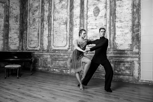 young couple in beautiful dance costumes dancing in the big hall