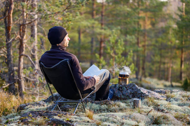 istock A man sits in a folding chair and reading a book outdoor. 1284538787