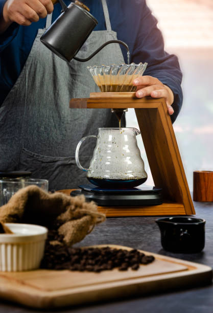 istock Coffee drip maker. Barista pouring hot water over coffee with paper filter 1284539403
