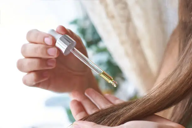 Photo of Hair care routine. Oil for head. Girl holding dropper