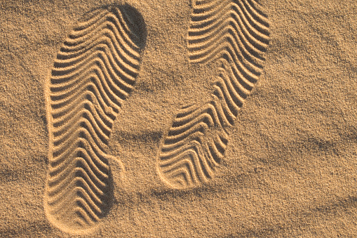 Shoe marks in the sand. Beautiful sand background with geometric pattern. Selective focus.