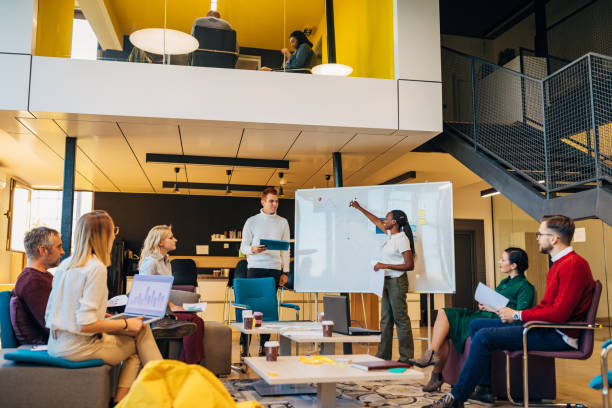 istock Confident female entrepreneur Black ethnicity giving whiteboard chart presentation during meeting with employee 1284543390