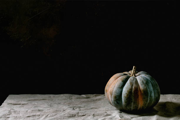 istock Blue pumpkin on linen tablecloth. Dark still life 1284543602