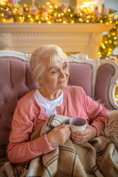 istock Senior woman sitting on a sofa with a cup of tea 1284543768